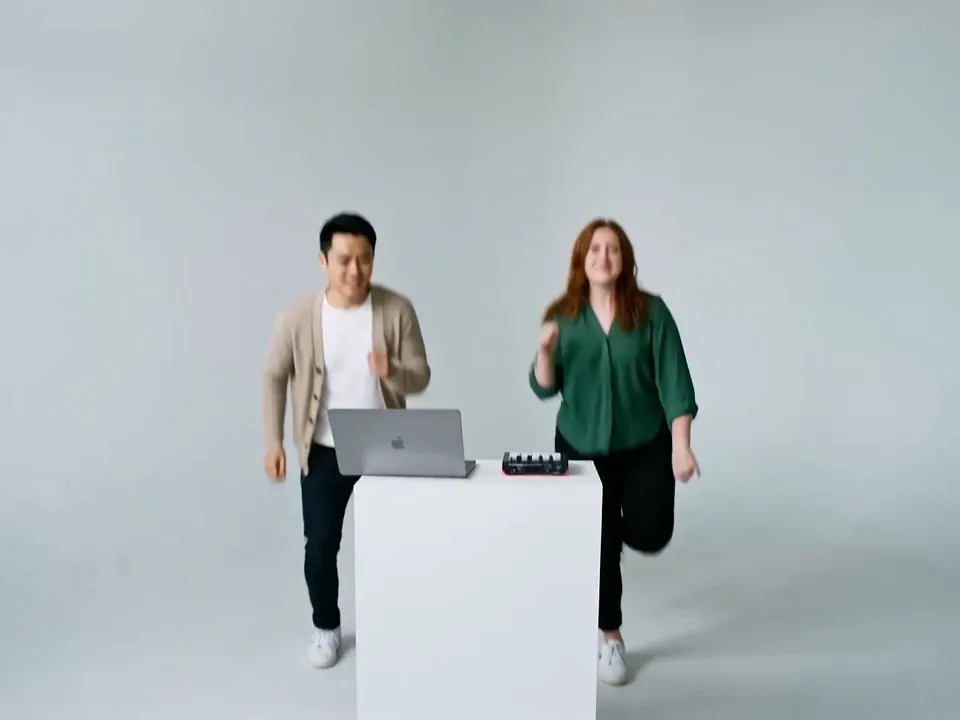 The Studio Sketch scene: a white backdrop and a white desk with a laptop and mini keyboard, with the same two people dancing beside it